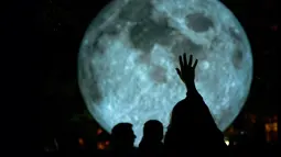 Seorang pengunjung berusaha menyentuh replika bulan raksasa yang dipajang di Bratislava, Slovakia, 7 Oktober 2017. Replika bulan tersebut merupakan karya seniman Inggris, Luke Jerram yang bertajuk 'Museum of The Moon'. (JOE KLAMAR / AFP PHOTO)
