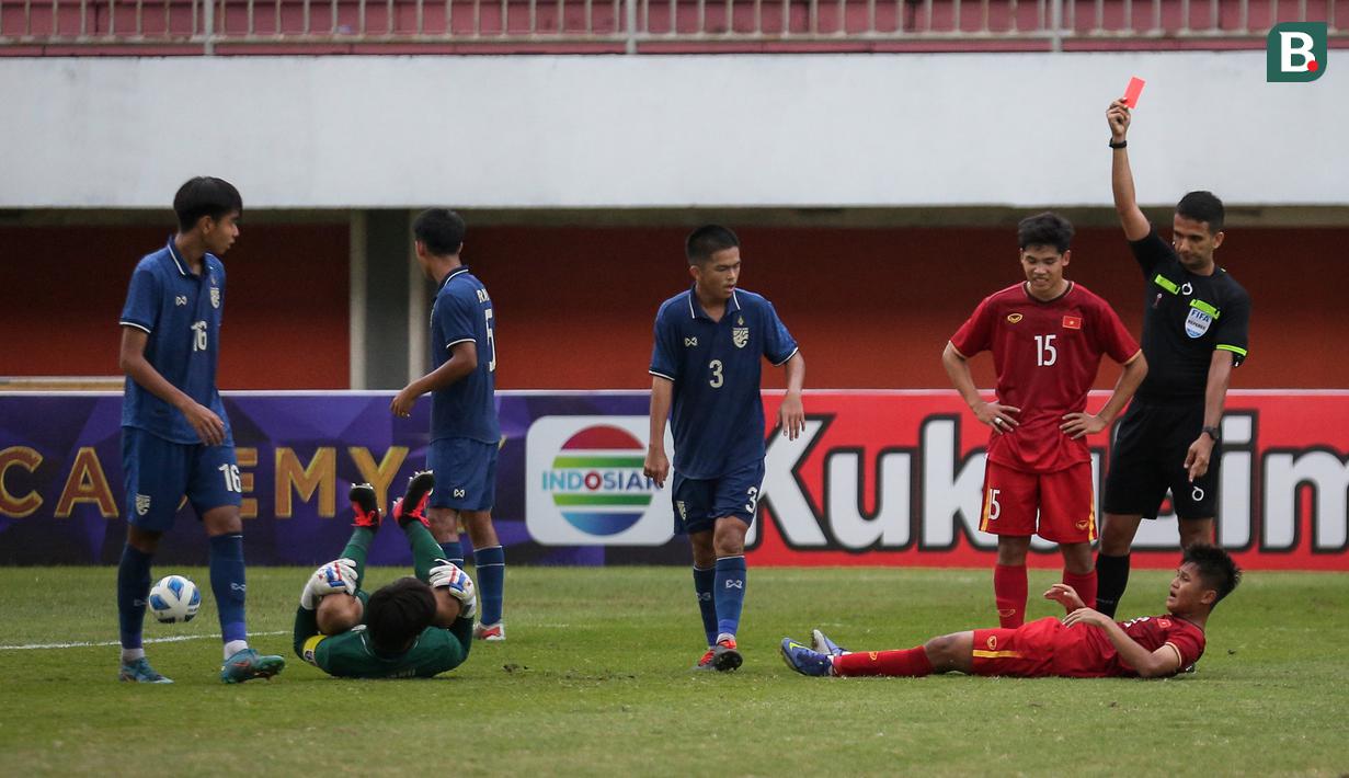 Wasit Thoriq Alkatiri memberikan kartu merah kepada pemain Vietnam U-16, Hoang Cong Hau (kanan bawah) usai melanggar kiper Thailand, Tissanu Khuptanawin dalam laga semifinal AFF U-16 2022 antara Thailand U-16 melawan Vietnam U-16 di Stadion Maguwoharjo, Sleman, Rabu (10/8/2022) sore WIB. (Bola.com/Bagaskara Lazuardi)