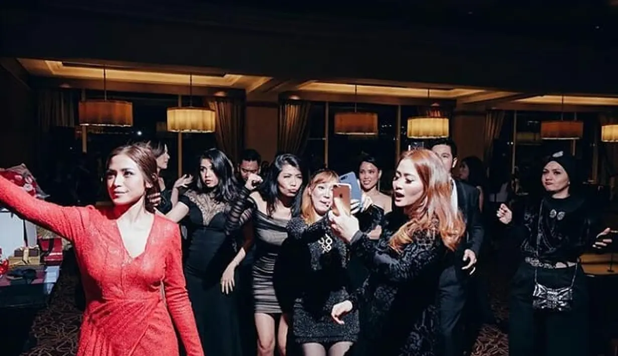 Yang punya hajat, Jedar tampak mempesona dengan dress panjang warna merah menerawang dengan belahan depan tinggi. Terlihat para tamu undangan yang hadir mengenakan warna hitam. (Instagram/inijedar)