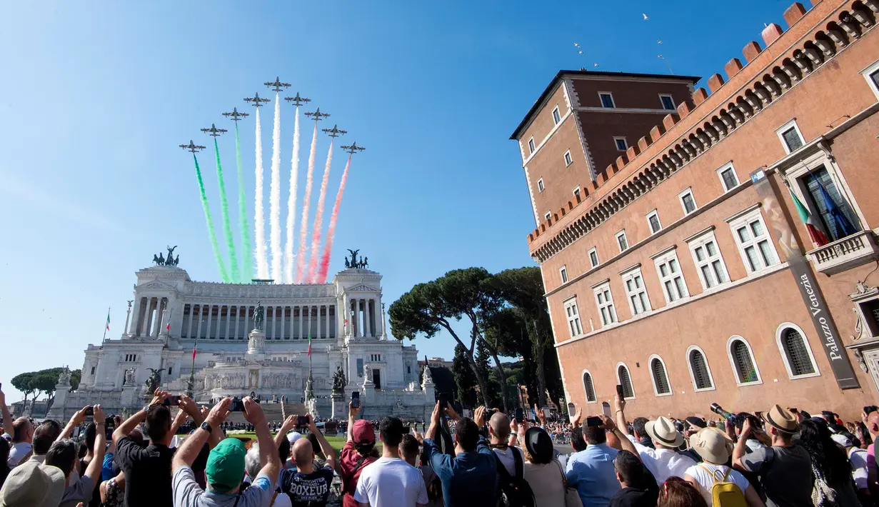 Warga menyaksikan aksi tim aerobatik Frecce Tricolori terbang mengeluarkan asap berwarna bendera Italia selama parade militer ulang tahun Hari Republik Italia ke-72 di Roma, Sabtu (2/6). (AP Photo/Claudio Peri)