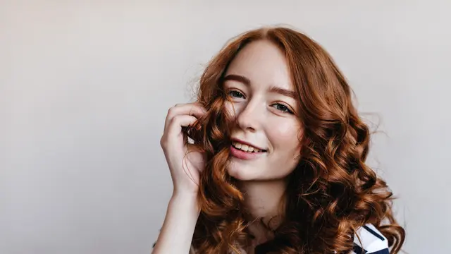Seorang perempuan dengan rambut keriting bergelombang (Foto Dok: Freepik/lookstudio)