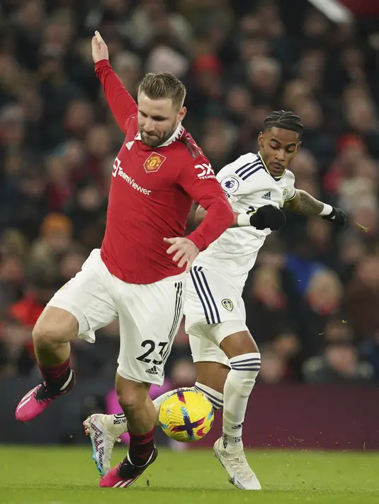 Bek Manchester United (MU) Luke Shaw berebut bola dengan penyerang Leeds United Crysencio Summerville pada laga tunda pekan ke-8 Liga Inggris 2022/2023 di Old Trafford, Manchester, Kamis (9/2/2023) dini hari WIB. Leeds menggandakan keunggulan di menit ke-47 gara-gara gol bunuh diri Raphael Varane. (AP Photo/Dave Thompson)