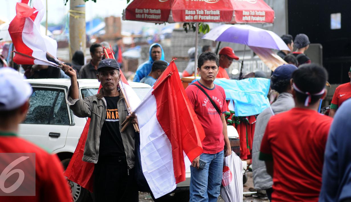 Pedagang menawarkan bendera kepada suporter Timnas Indonesia di sekitar Stadion Pakansari, Bogor, Sabtu (3/12). Timnas Indonesia akan melakoni laga semifinal pertama Piala AFF 2016 melawan Vietnam. (Liputan6.com/Helmi Fithriansyah)