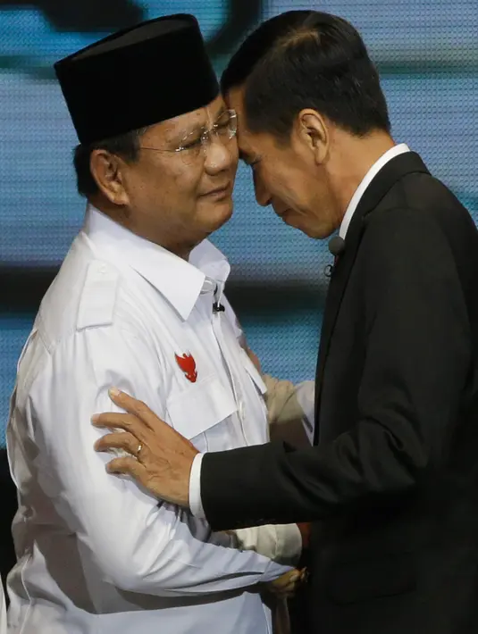 Dua calon Presiden Indonesia, Joko Widodo (Jokowi) dari Partai PDIP dan Prabowo Subianto dari Partai Gerindra saling merangkul selama sesi debat pilpres 2014 di Jakarta pada 9 Juni 2014. (AP Photo/Dita Alangkara)