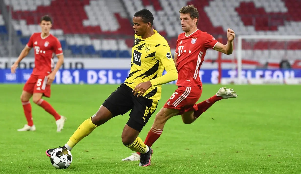 Pemain Borussia Dortmund, Manuel Akanji berebut bola dengan penyerang Bayern Munchen, Thomas Mueller pada laga Piala Super Jerman di Allianz Arena, Kamis (1/10/2020). Bayern Munich sukses meraih trofi juara Piala Super Jerman 2020 berkat kemenangan 3-2 atas Borussia Dortmund (Sven Hoppe/Pool via AP)