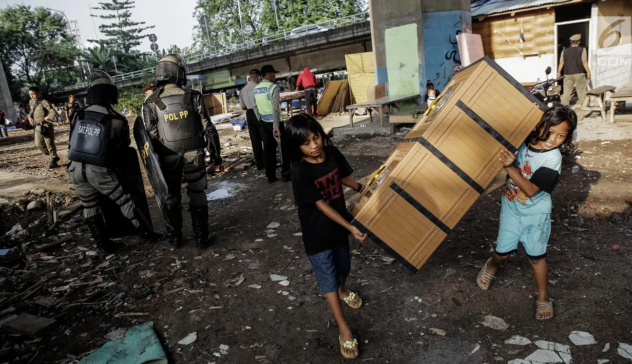 Dua orang anak menyelamatkan barangnya saat penertiban di bawah kolong Tol Teluk Intan, Jakarta, Rabu (14/6). Gubernur DKI Jakarta Djarot Saiful Hidayat menegaskan, kawasan tersebut dilarang digunakan sebagai tempat pemukiman. (Liputan6.com/Faizal Fanani)