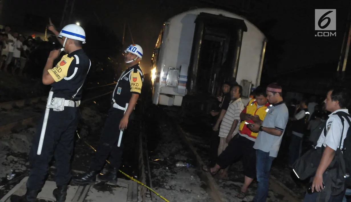 Petugas meminta warga untuk menjauhi lokasi kecelakaan di perlintasan Kramat, Senin, Jakarta, Selasa (13/6). Akibat dari kecelakaan ini, kondisi mobil hancur dan satu gerbong kereta api ikut terbakar. (Liputan6.com/Helmi Afandi)