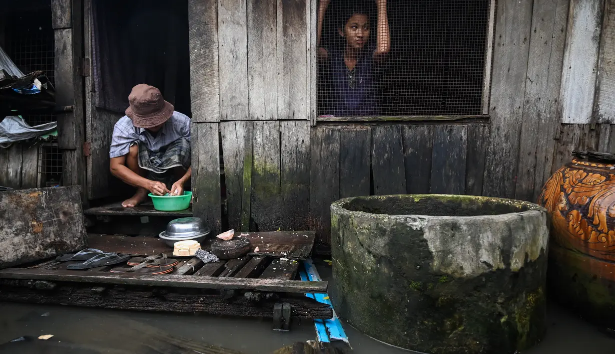 Seorang gadis melihat keluar dari rumahnya yang dikelilingi oleh air banjir di pinggiran Yangon (17/8/2022). Sebagian besar kotapraja di Yangon dilanda banjir yang menyebabkan kemacetan lalu lintas pada jam-jam sibuk. (AFP/Stringer)