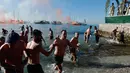 Angelos Filoxenidis memegang sebuah salib kayu setelah mengambilnya dari air dari pantai pinggiran pesisir Athena selama Hari Epiphany Orthodox, Yunani (6/1). (AFP Photo/Louisa Gouliamaki)