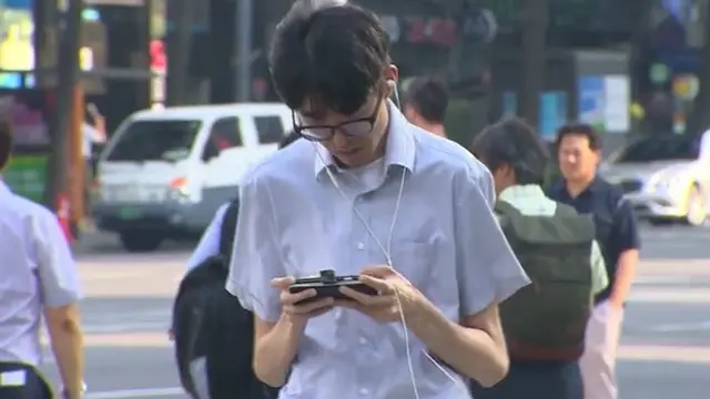 Seorang pria bermain ponsel sambil berjalan kaki