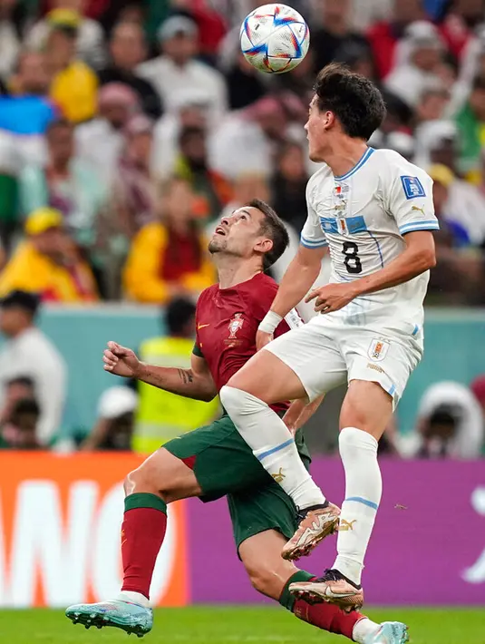 Pemain Uruguay Facundo Pellistri (kiri) berebut bola dengan pemain Portugal Raphael Guerreiro pada pertandingan sepak bola Grup H Piala Dunia 2022 di Stadion Lusail, Lusail, Qatar, 28 November 2022. Portugal mengalahkan Uruguay dengan skor 2-0. (AP Photo/Martin Meissner)