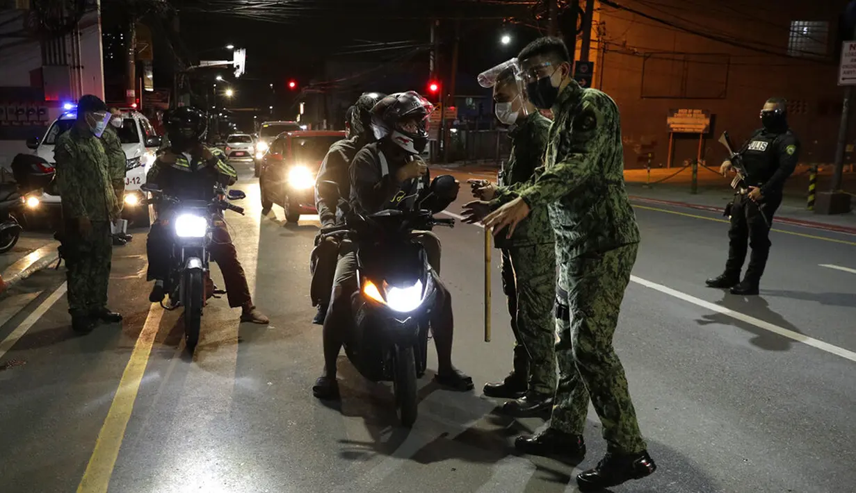Polisi memeriksa pengendara sepeda motor saat jam malam untuk mencegah penyebaran COVID-19 di Metro Manila, Filipina, Senin (15/3/2021). Kementerian Kesehatan Filipina melaporkan lonjakan kasus COVID-19 selama lebih dari seminggu. (AP Photo/Aaron Favila)