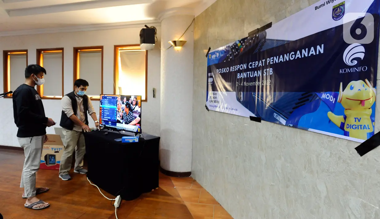 Petugas Kementerian Komunikasi dan Informatika (Kemenkominfo) menyampaikan penjelasan penggunaan alat Set Top Box (STB) yang dibagikan secara gratis kepada warga di Posko Respon Cepat Penanganan Bantuan STB di Hotel Bumi Wiyata, Depok, Jawa Barat, Rabu (2/11/2022). Kemenkominfo membuka posko penanganan bantuan STB sebagai perangkat konverter siaran TV digital ke televisi jenis analog bagi warga Jabodetabek yang akan mengikuti Analog Switch Off (ASO) di 2 November 2022 tengah malam. (merdeka.com/Arie Basuki)