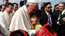 Seorang anak perempuan memeluk Paus Fransiskus saat menyambut kedatangannya di Bandara Internasional Yangon, Myanmar (27/11). Kedatangan Paus Fransiskus disambut oleh ribuan umat Katolik Roma yang memenuhi Yangon. (AFP Photo/Vincenzo Pinto)