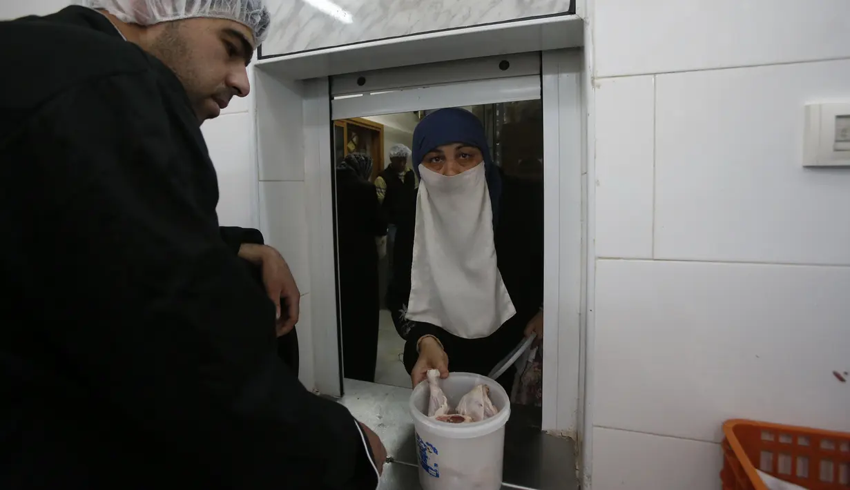 Seorang wanita Palestina menerima makanan buka puasa gratis di sebuah dapur amal, kota Hebron, Tepi Barat, Minggu (20/5). Banyak dari warga Palestina yang mengandalkan makanan gratis karena situasi ekonomi keluarga yang buruk. (AFP/HAZEM BADER)