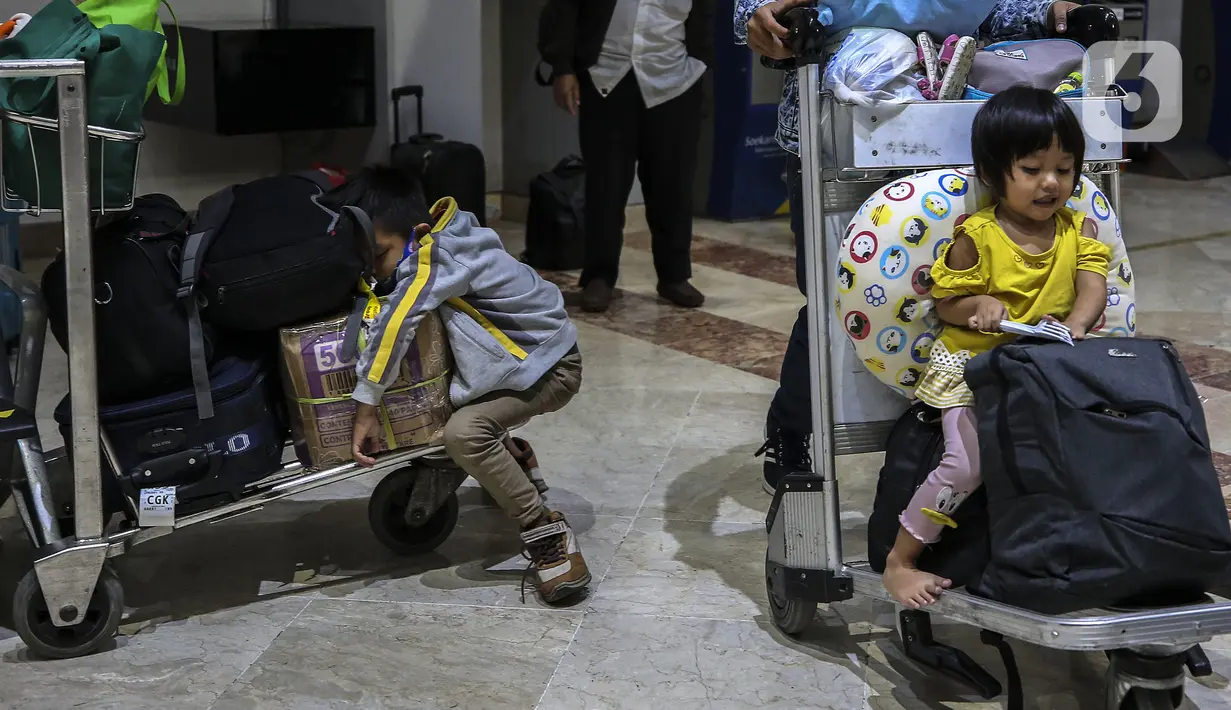 Anak-anak calon penumpang pesawat duduk di atas barang bawaan di Terminal 2 Bandara Soekarno Hatta, Tangerang, Banten, Rabu (5/5/2021). Pergerakan penumpang H-1 jelang larangan mudik diprediksi berjumlah 86.000 penumpang atau naik 15 persen dibanding hari kemarin. (Liputan6.com/Johan Tallo)