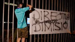 Suporter memasang spanduk saat melakukan protes di depan kantor Barcelona, Selasa (25/8/2020). Aksi tersebut merupakan respon fans atas kabar Lionel Messi yang akan meninggalkan Camp Nou pada musim panas ini. (AFP/Pau Barrena)