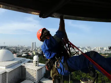 Salah satu relawan pecinta alam membersihkan atap menara Masjid Istiqlal, Jakarta, Jumat (17/2). Menyambut Milad Masjid Istiqlal ke-39, relawan pecinta alam bantu membersihkan Masjid Istiqlal. (Liputan6.com/Helmi Fithriansyah)