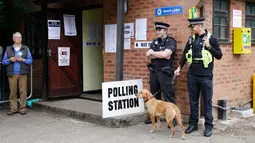 Anggota kepolisian bersama seekor anjing berjaga di TPS Kota Maidenhead, Kamis (8/6). Pemilu Inggris dimulai dengan penjagaan ketat menyusul dua serangan teror yang merenggut 30 jiwa dalam waktu kurang dua pekan. (AP Photo/Alastair Grant)