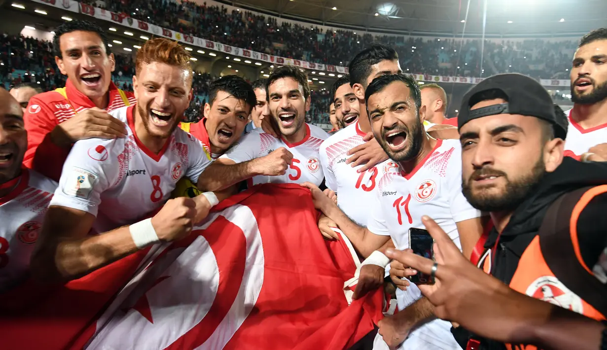 Pemain tim nasional sepak bola Tunisia melakukan selebrasi usai pertandingan melawan Libya di kualifikasi Piala Dunia 2018 di Stadion Olimpiade Rades, Tunisia (11/11). Tunisia berhasil lolos ke Piala Dunia 2018. (AFP Photo/Fethi Belaid)