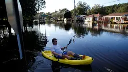 Parker Uzzell menggunakan kano untuk beraktivitas di tengah banjir yang merendam wilayah Lumberton di Carolina Utara, Amerika Serikat, 12 Oktober 2016. Banjir akibat badai Matthew tersebut merendam kota berpenduduk 21.000 orang itu. (REUTERS/Randall Hill)