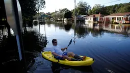Parker Uzzell menggunakan kano untuk beraktivitas di tengah banjir yang merendam wilayah Lumberton di Carolina Utara, Amerika Serikat, 12 Oktober 2016. Banjir akibat badai Matthew tersebut merendam kota berpenduduk 21.000 orang itu. (REUTERS/Randall Hill)