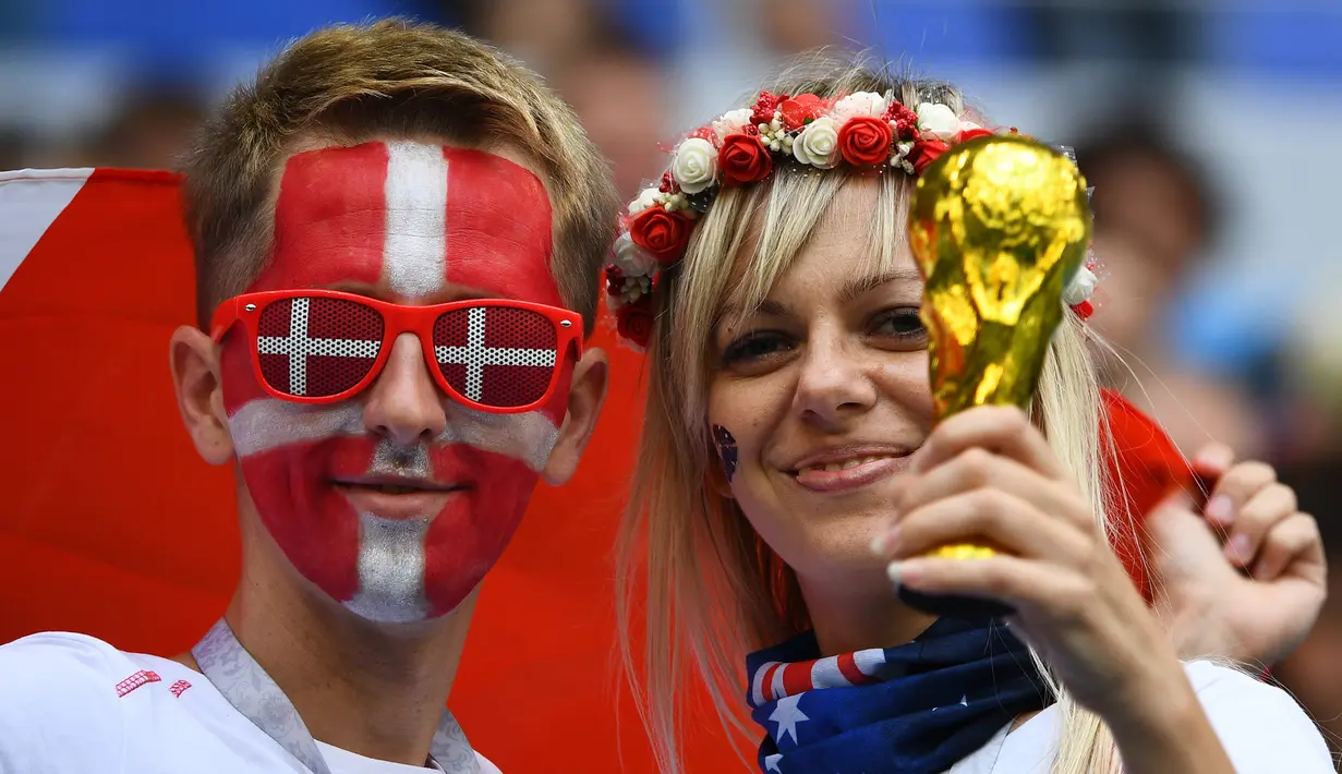 Sepasang suporter Denmark membawa miniatur trofi saat negaranya melawan Australia pada laga grup C Piala Dunia di Samara Arena, Samara, Kamis (21/6/2018). Cerita sepenggal kisah romantis saat Piala Dunia 2018 Rusia. (AFP/Manan Vatsyayana)