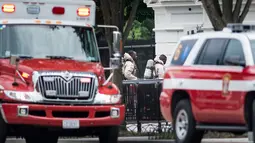 Petugas darurat dengan baju pelindung berjalan menuju gerbang bagian utara Gedung Putih, Washington, DC, Senin (30/5). Gedung Putih ditutup sebagian untuk menyelidiki sebuah benda mencurigakan yang dilemparkan melalui pagar. (Brendan Smialowski/AFP)