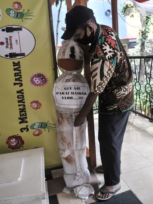 Pekerja memasang boneka pocong di Kantor Kecamatan Senen, Jakarta, Kamis (13/8/2020). Pemkot Jakpus menyiapkan peti mati dan boneka pocong untuk dipajang di setiap kecamatan sebagai peringatan akan bahaya Covid-19 dan imbauan untuk tidak mengabaikan protokol kesehatan. (merdeka.com/Iqbal Nugroho)