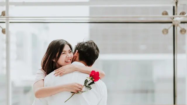 Wanita cantik terlihat bahagia setelah diberikan bunga mawar oleh pasangannya