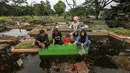 Genangan air yang menutupi area pemakaman membuat akses jalan antar-blok makam menjadi terbatas. Peziarah harus ekstra hati-hati melewati lumpur dan air yang masih menggenang. Tampak dalam foto, warga mengunjungi makam anggota keluarga mereka di Tempat Pemakaman Umum (TPU) Semper, Cilincing, Jakarta Utara pada 15 Februari 2026. (Syinatria RESPATI/AFP)