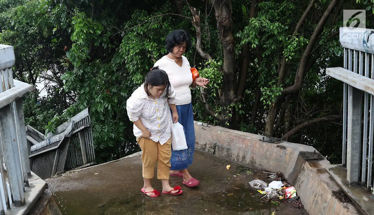 Pejalan kaki melintasi JPO yang rusak di Terminal Kampung Rambutan, Jakarta, Senin (28/1). Kondisi JPO yang sebagian pagar pembatasnya rusak tersebut membahayakan pejalan kaki apabila tidak segera diperbaiki. (Liputan6.com/Immanuel Antonius)