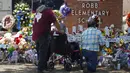 Orang-orang memberikan penghormatan dalam sebuah peringatan di luar Robb Elementary School untuk menghormati para korban yang tewas dalam penembakan di sekolah pekan ini di Uvalde, Texas, Amerika Serikat, 28 Mei 2022. (AP Photo/Dario Lopez-Mills)