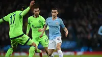 Pemain Man City, Phil Foden mencoba melewati hadangan pemain Schalke pada leg kedua, babak 16 besar Liga Champions yang berlangsung di Stadion Etihad, Manchester, Rabu (13/3). Man City menang 7-0 atas Schalke. (AFP/Oli Scarff)