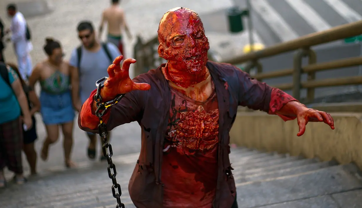Peserta berdandan layaknya zombie dan menakut-nakuti orang selama acara Zombie Walk di Sao Paulo, Brasil, Sabtu (2/11/2019). Ratusan orang turun ke jalan memakai kostum karakter horor pada acara tahunan yang digelar sejak 2006 pada Hari Para Arwah. (Miguel SCHINCARIOL / AFP)
