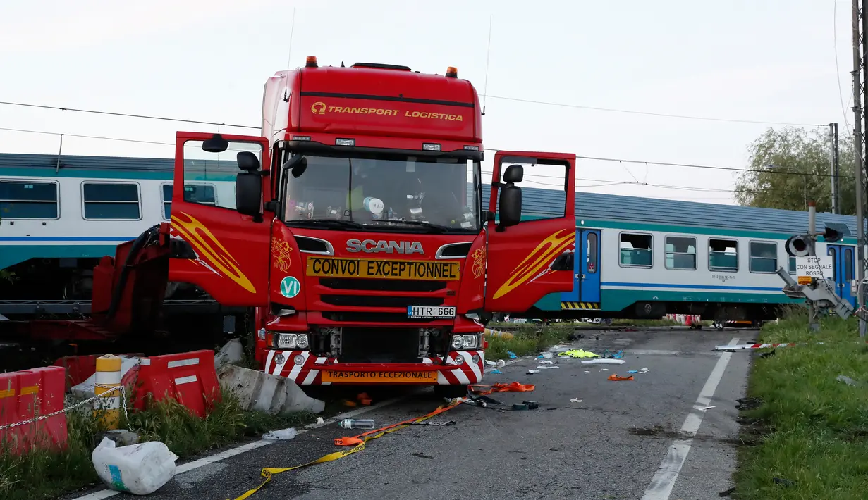 Bangkai sebuah truk terlihat di sebelah rangkaian kereta api yang keluar jalur setelah terlibat kecelakaan di dekat wilayah Turin, Italia, Kamis (24/5). Truk itu dihantam kereta yang mengakibatkan dua orang tewas dalam kejadian ini. (AP/Antonio Calanni)