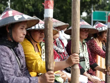 Sejumlah petani Pegunungan Kendeng menabuh lesung saat menggelar aksi di depan Istana Merdeka, Jakarta, Rabu (12/4). Mereka meminta Pemerintah untuk menghentikan pembangunan dan pabrik semen di Pegunungan Kendeng. (Liputan6.com/Faizal Fanani)