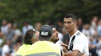 Seorang suporter berusaha memeluk penyerang Juventus, Cristiano Ronaldo selama pertandingan persahabatan antara Juventus A dan tim B, di Villar Perosa, Italia utara, (12/8). Pada pertandingan ini Ronaldo mencetak satu gol. (AFP Photo/Isabella Bonotto)