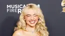Saat naik ke atas panggung untuk menerima trofi, ia tampil anggun dengan gaun strapless panjang yang dihiasi perhiasan, dilengkapi dengan kalung berlian dan cincin besar yang serasi. [@sabrinacarpenter/@mtv].