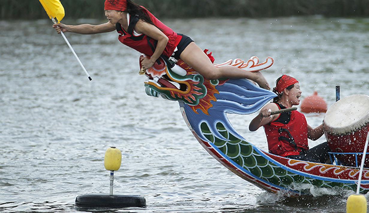 Seorang peserta lomba perahu naga di Taiwan mencoba meraih bendera di garis finis. (AP Photo/Wally Santana)
