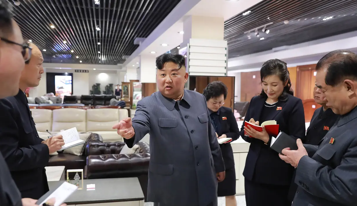 Pemimpin Korea Utara, Kim Jong-un berbincang dengan stafnya ketika berada di toko furniture saat mengunjungi Taesong Department Store setelah dibuka untuk umum di Korea Utara (8/4). (KCNA VIA AFP Photo)