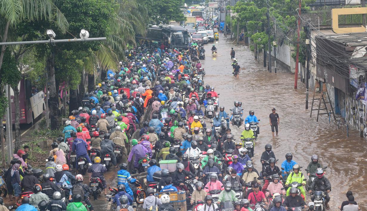 Pemerintah Provinsi DKI Jakarta berupaya menanggulangi situasi ini dengan melakukan operasi modifikasi cuaca untuk mengurangi intensitas hujan. Tampak dalam foto, antrean pengendara motor yang mencoba menerobos banjir di Jalan Daan Mogot, Jakarta, Jumat (23/1/02026). (merdeka.com/ Arie Basuki)