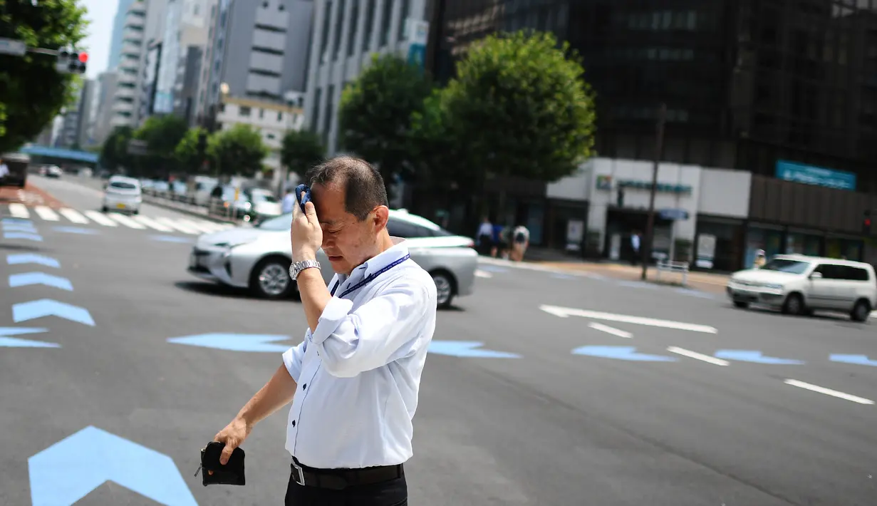 Seorang pria menyeka wajahnya saat berjalan selama gelombang panas melanda Tokyo, Jepang (1/8/2019). Cuaca panas ekstrem yang melanda Jepang telah menewaskan puluhan orang tewas dan menyebabkan ribuan orang masuk rumah sakit dengan gejala dehidrasi. (AFP Photo/Charly Triballeau)