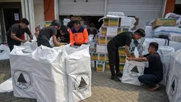 Tak hanya barang, Pemprov Jatim juga menggelontorkan bantuan uang senilai total Rp 10,5 miliar untuk tiga provinsi terdampak bencana, yakni Sumatera Utara, Sumatera Barat, dan Aceh. Tampak dalam foto, para relawan mengemasi perlengkapan untuk dikirimkan ke daerah-daerah terdampak banjir di Badan Penanggulangan Bencana Daerah (BPBD) Sidoarjo, Provinsi Jawa Timur, pada Jumat 5 Desember 2025. (JUNI KRISWANTO/AFP)