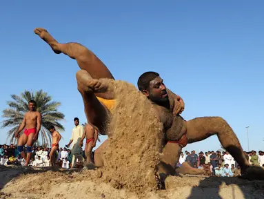 Seorang pegulat Pakistan membanting lawannya saat bertarung dalam kompetisi gulat Greco-Roman mingguan di Dubai (16/3). Mereka melakukan pertandingan gulat gaya kuno. (AFP Photo/Karim Sahib)
