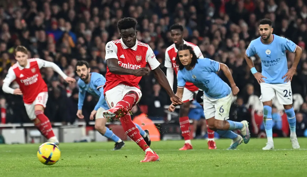 Pemain Arsenal, Bukayo Saka mencetak gol penyeimbang 1-1 dari tendangan penalti ke gawang Manchester City pada laga pekan ke-23 Liga Inggris 2022/2023 yang berlangsung di Emirates Stadium, London, Kamis (16/02/2023) WIB. (AFP/Glyn Kirk)