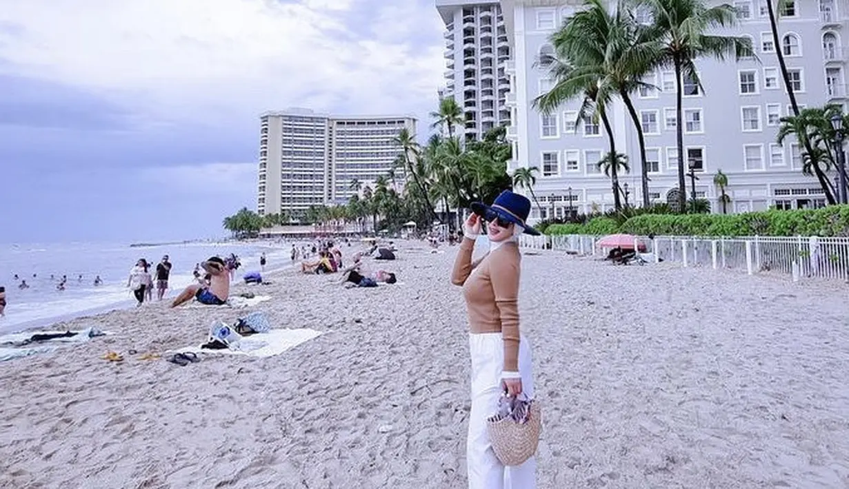 Berada di pantai Hawaii, Syahrini mengenakan atasan lengan coklat dipadukan celana putih. Ia mengenakan topi hitam. [Instagram/@princessyahrini]