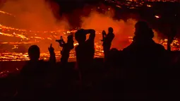 Orang-orang menyaksikan aliran lahar dari letusan gunung berapi di Semenanjung Reykjanes, barat daya Islandia, Senin (29/3/2021). Letusan gunung berapi tersebut tidak dipandang sebagai ancaman bagi kota-kota sekitar dan warga yang menyaksikan dari dekat. (AP Photo/Marco Di Marco)