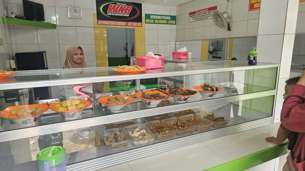 Pelayan rumah makan saat memberikan layanan makanan kepada pembeli di Kota Depok.