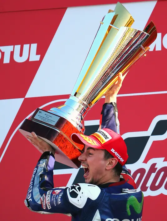 Jorge Lorenzo mengangkat piala usai sukses menjadi juara dunia MotoGP 2015 di seri terakhir Grand Prix Valencia Spanyol, Minggu (8/11). Lorenzo berhasil finis terdepan, disusul Marc Marquez dan Dani Pedrosa. (REUTERS/Heino Kalis)
